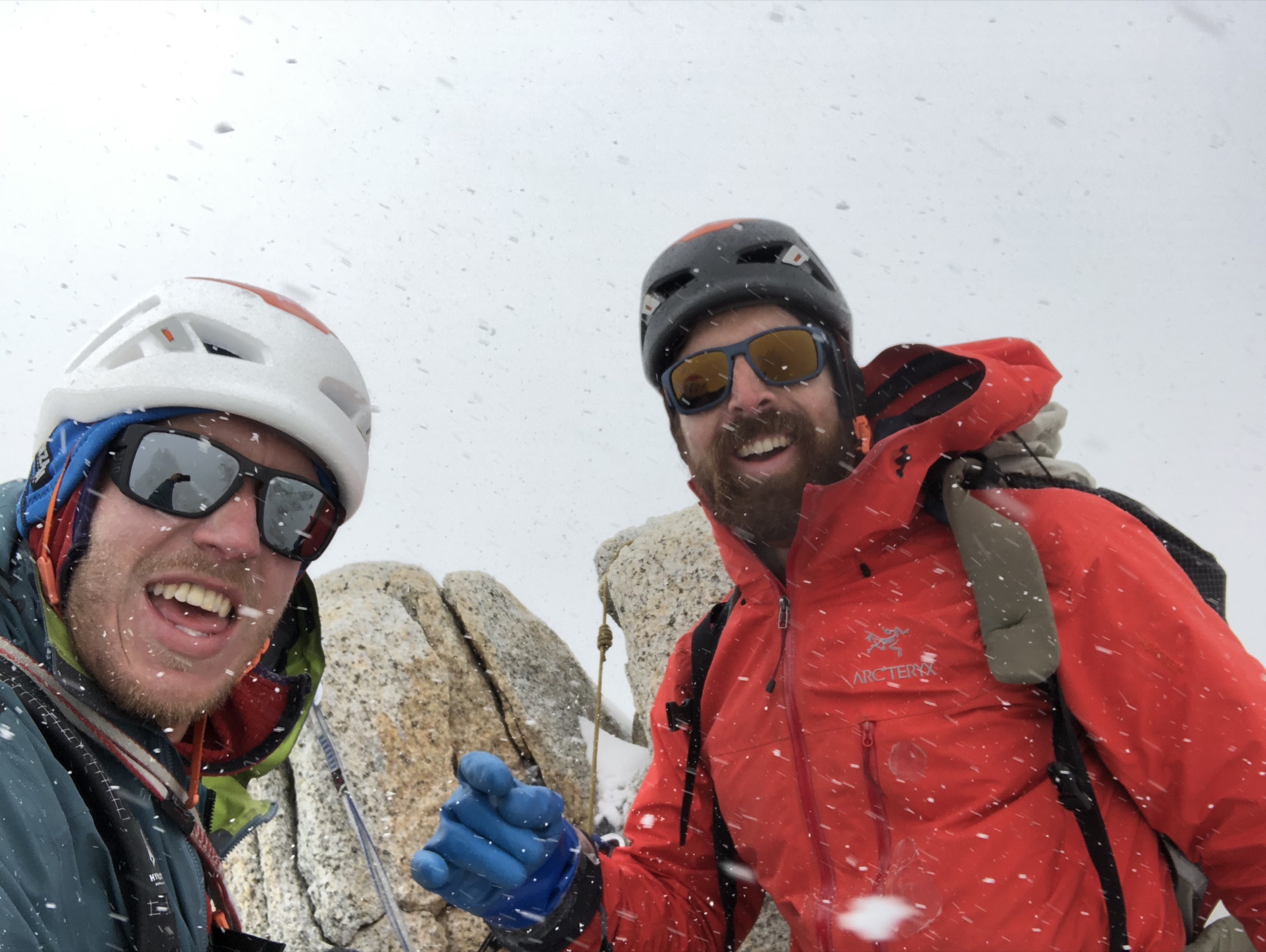Two climbers smiling together on a summit