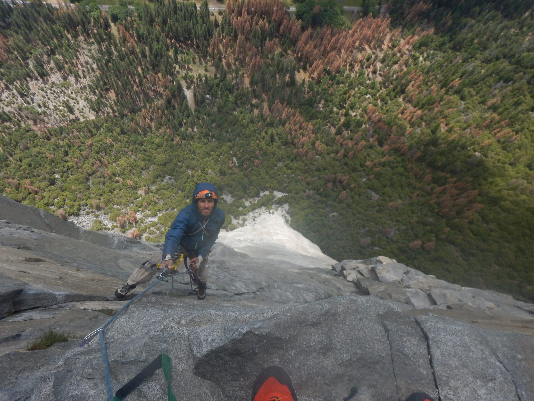 View down past a climber ascending a steep Yosemite wall