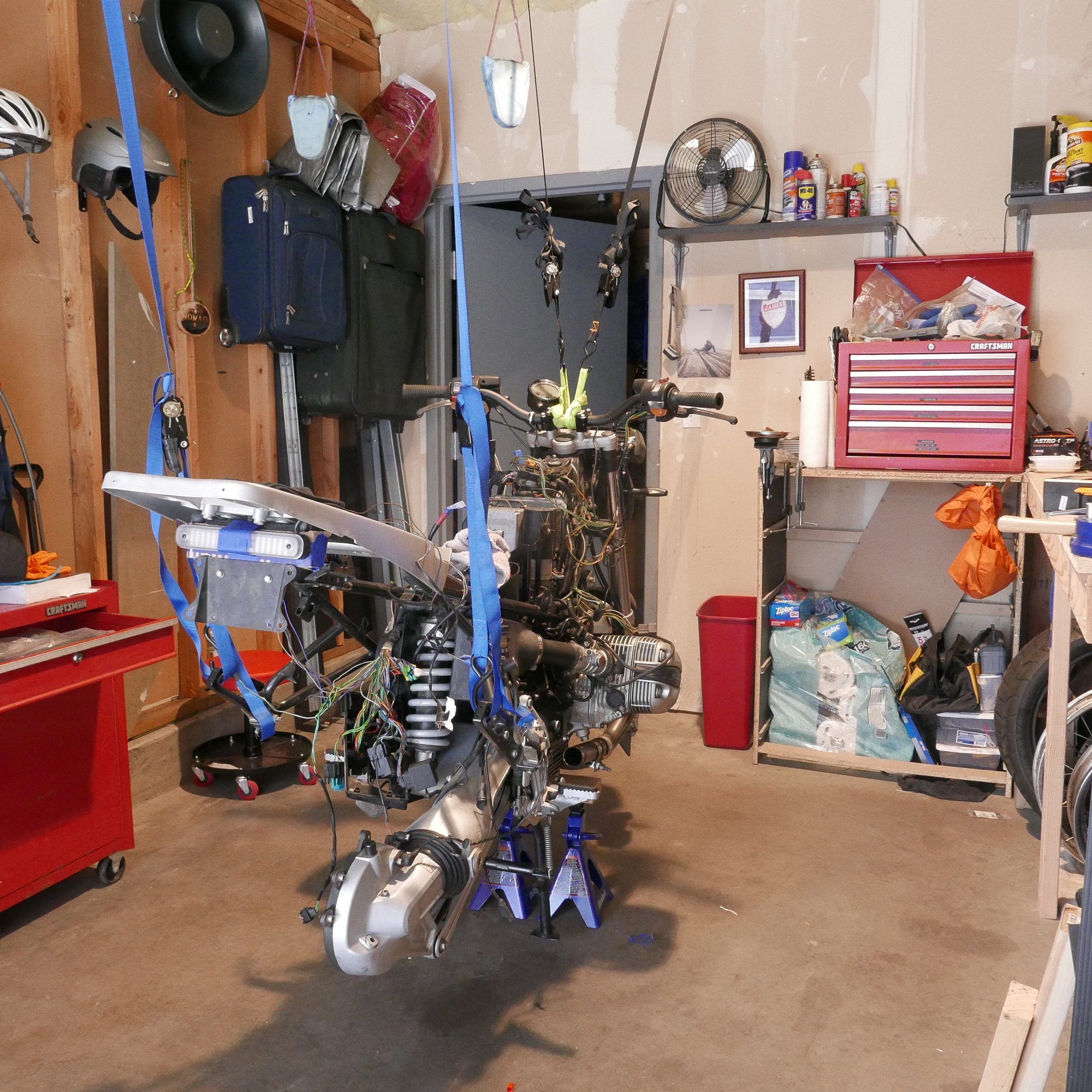 BMW motorcycle disassembled and suspended by straps in a garage