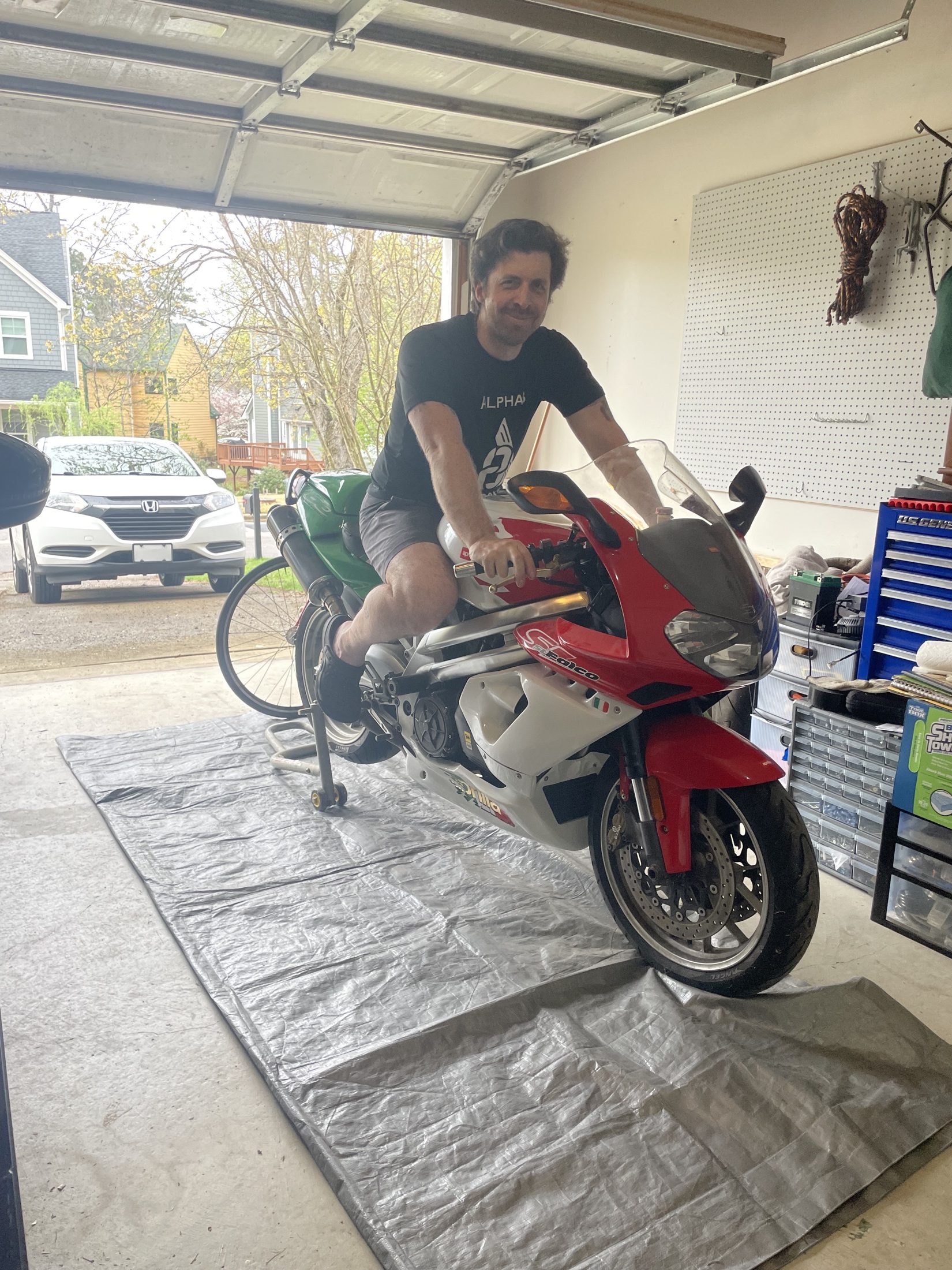 Jay sitting on a red Aprilia Falco in a garage