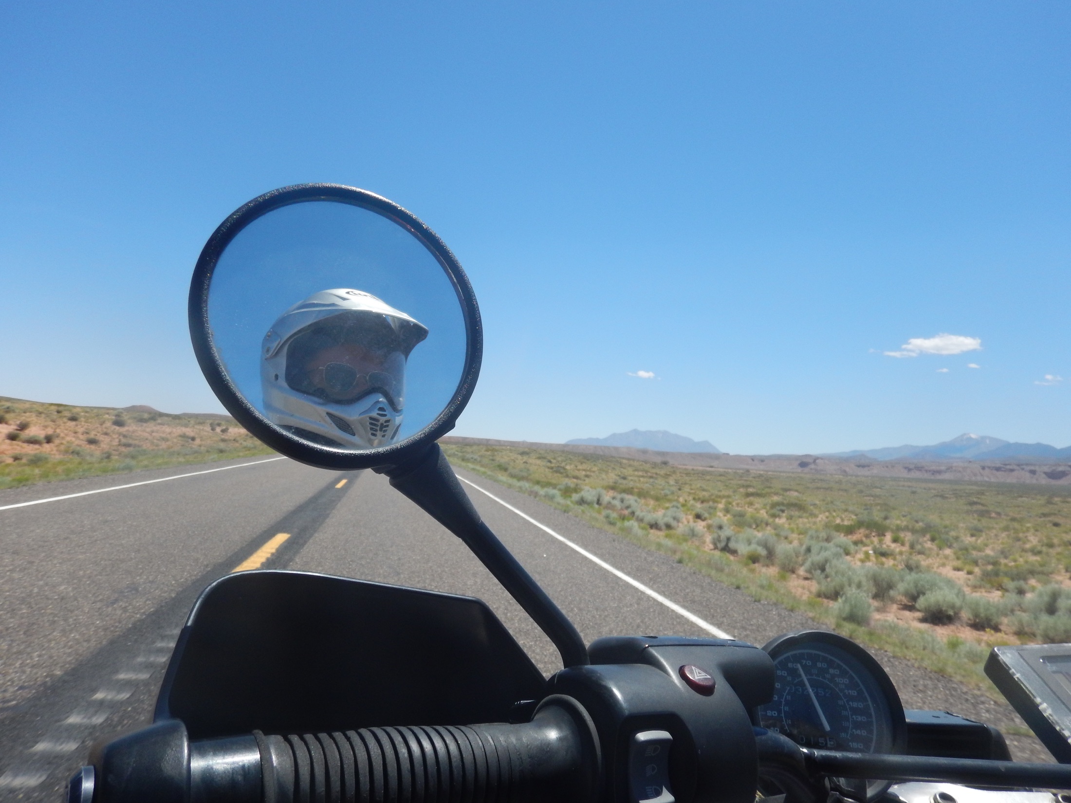 Helmeted rider reflected in a motorcycle mirror